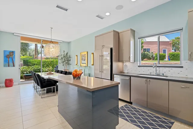 a kitchen with stainless steel appliances granite countertop a stove a sink a refrigerator and a dining table with the view of living room