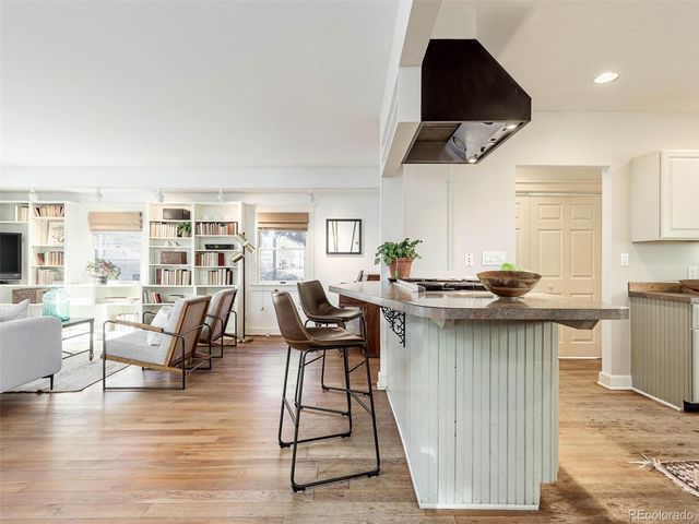 a kitchen with stainless steel appliances granite countertop a stove a sink dishwasher and a dining table with wooden floor