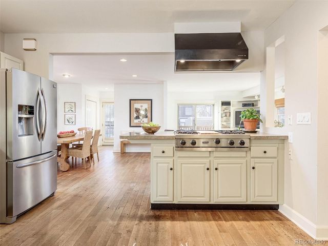 a kitchen with stainless steel appliances a stove a sink dishwasher a refrigerator and white cabinets with wooden floor
