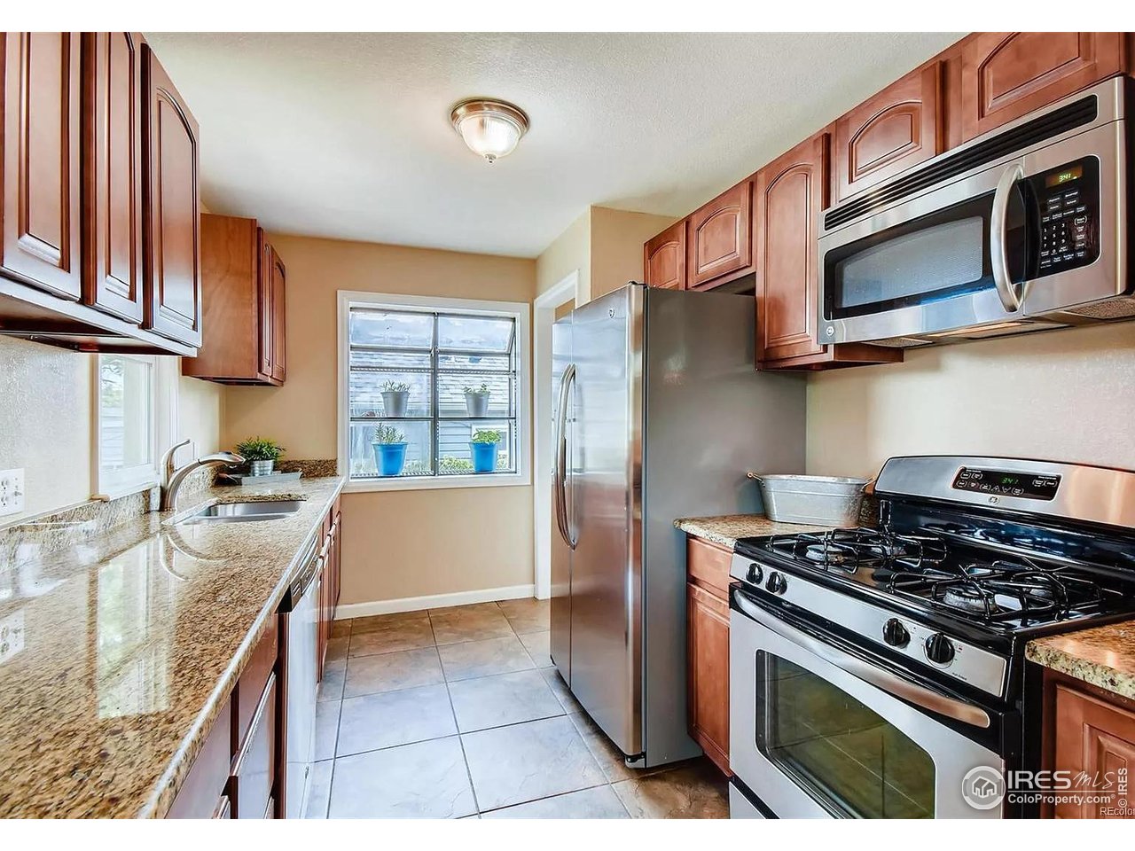 4870 Irving Street Denver, CO 80221 - Photo 6 of 19 a kitchen with stainless steel appliances granite countertop a stove and a microwave
