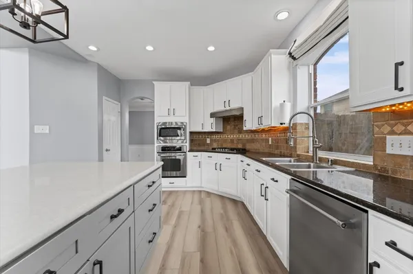 a kitchen with granite countertop white cabinets and stainless steel appliances