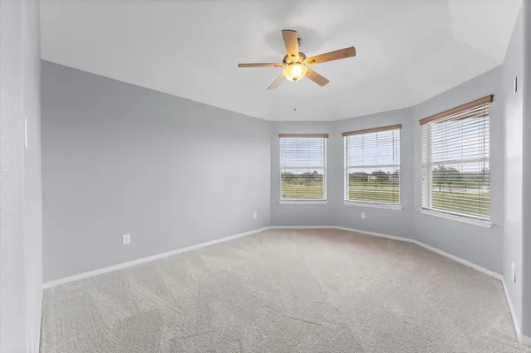 a view of an empty room with chandelier fan and fire place