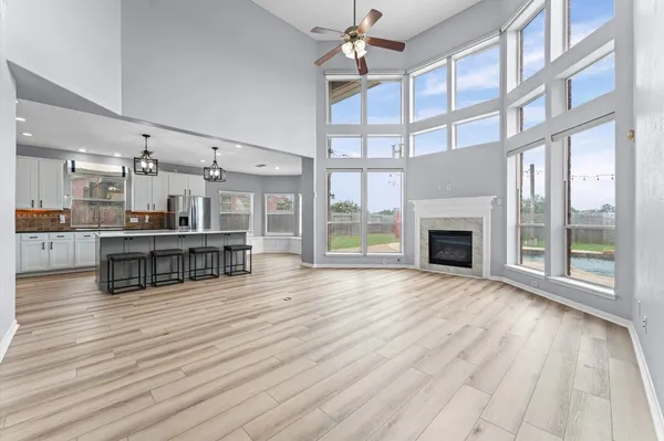 a view of an empty room with wooden floor fireplace and a window