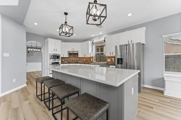 a living room with stainless steel appliances kitchen island wooden floors and living room view
