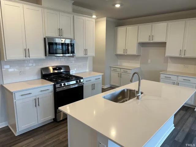 a kitchen with stainless steel appliances a sink a stove a microwave and cabinets