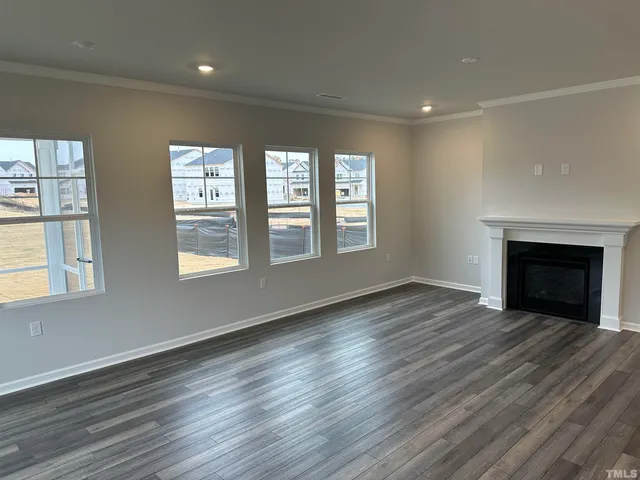 an empty room with wooden floor fireplace and windows
