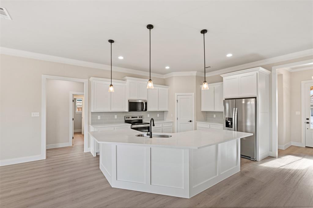 506 Limestone Circle Mabank, TX 75147 - Photo 7 of 33 a kitchen with stainless steel appliances kitchen island a refrigerator a sink dishwasher a oven with white cabinets and wooden floor