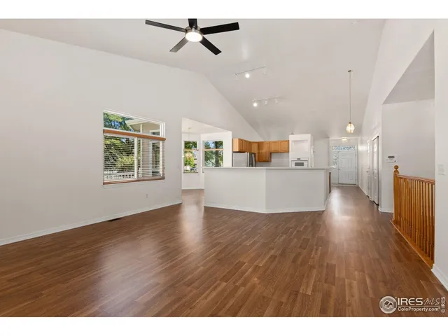 a view of a kitchen and an empty room with wooden floor