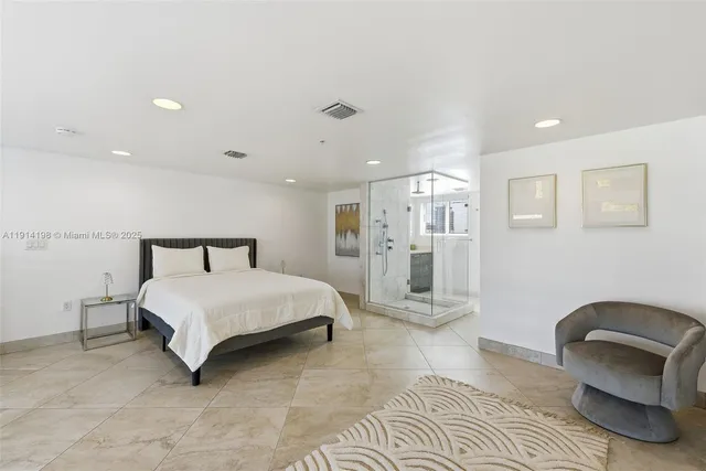 a spacious bedroom with a bed a couch and a chair