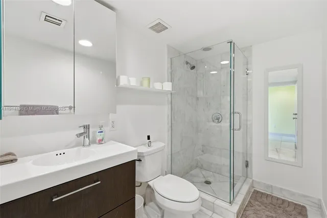 a bathroom with a double vanity sink toilet mirror and shower