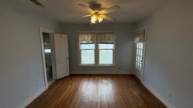 an empty room with wooden floor and windows