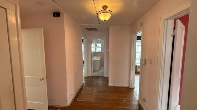 a view of a hallway with wooden floor and a chandelier