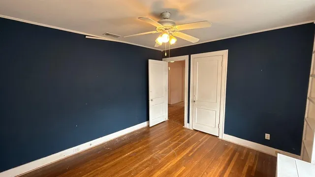 an empty room with a ceiling fan and wooden floor