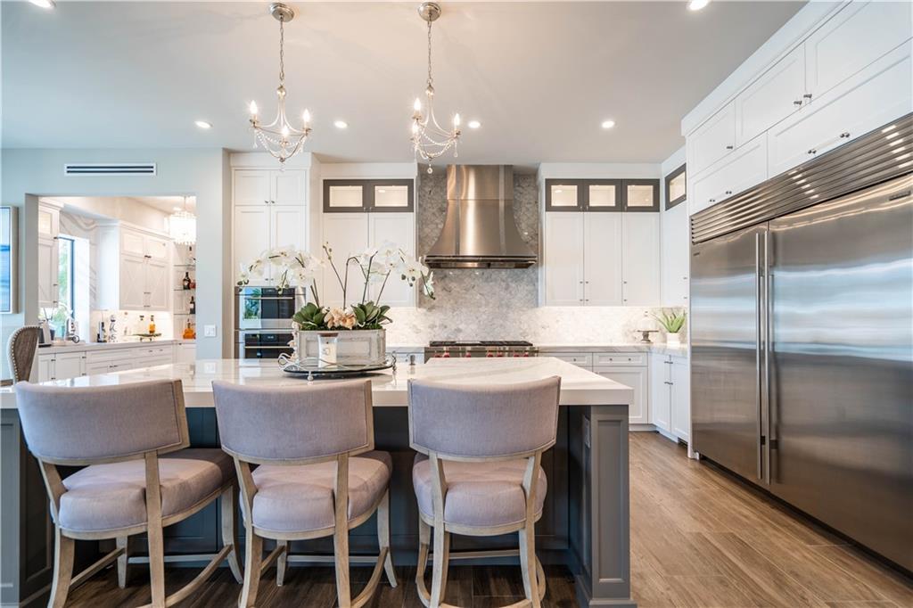 2349 Northeast 24th Street Lighthouse Point, FL 33064 - Photo 15 of 85 a kitchen with kitchen island granite countertop a dining table chairs refrigerator and sink