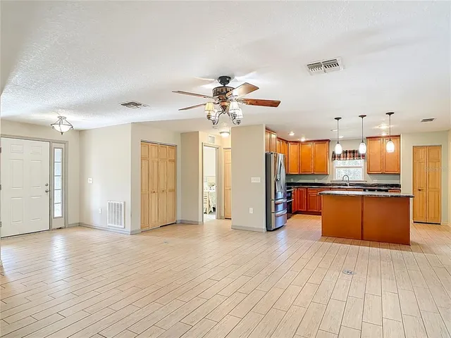 a view of a kitchen with kitchen island stainless steel appliances wooden floor