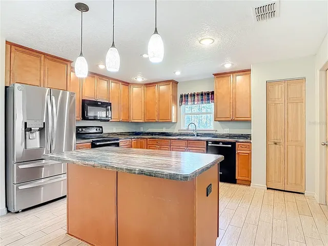 a kitchen with stainless steel appliances granite countertop a refrigerator a stove and a sink with wooden floor
