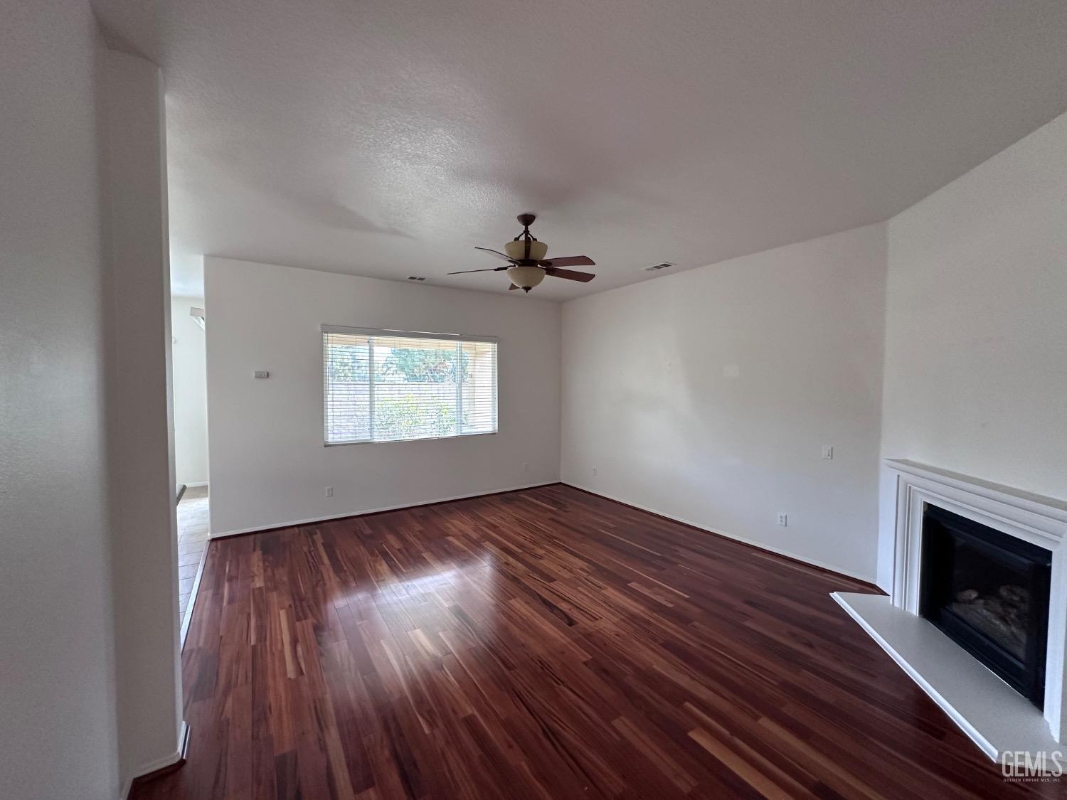 Undisclosed Address Bakersfield, CA 93306 - Photo 14 of 43 an empty room with wooden floor a fireplace and windows