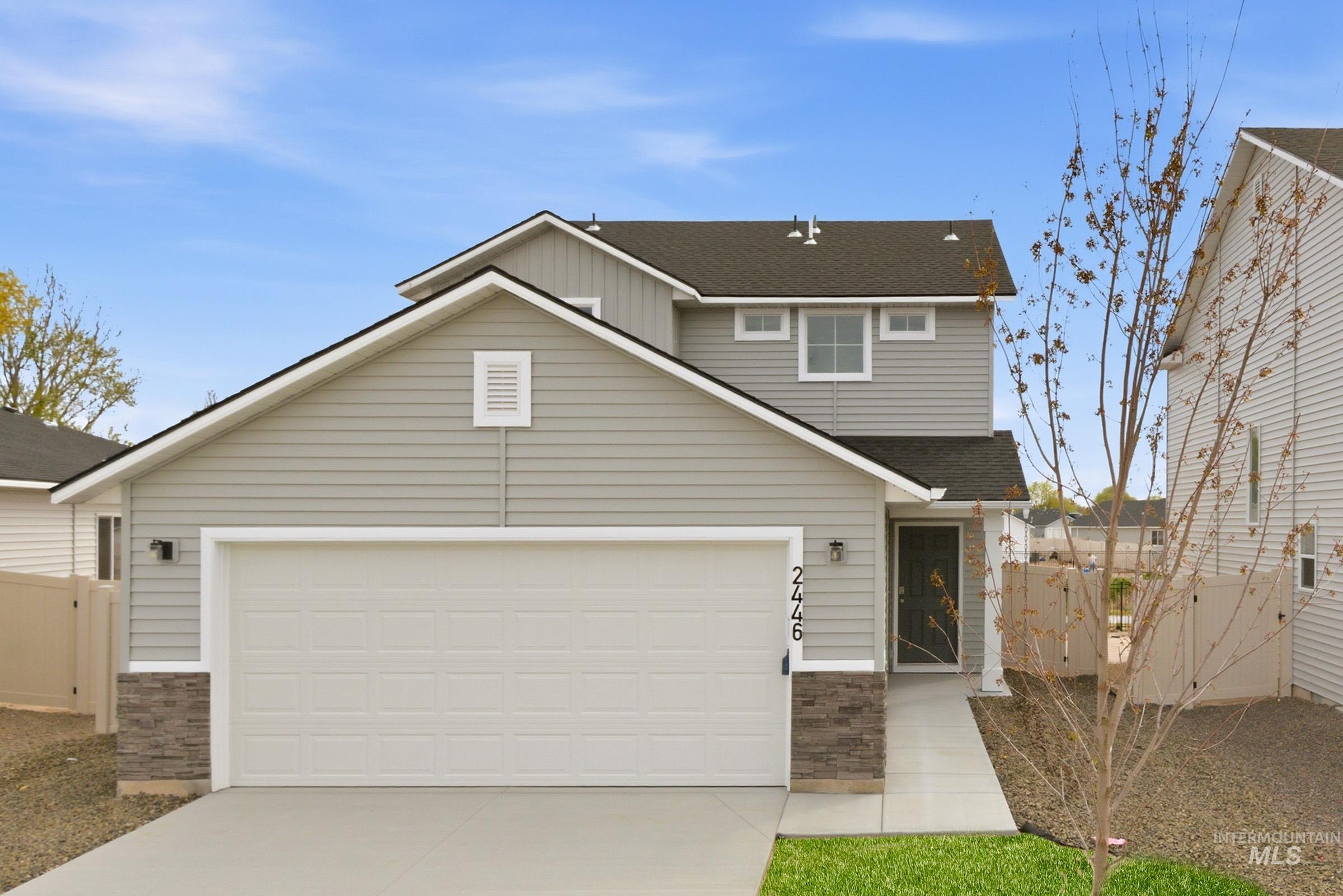 2446 West Fallon Loop Nampa, ID 83651 - Photo 1 of 19 Traditional-style house featuring a shingled roof, driveway, stone siding, and a garage