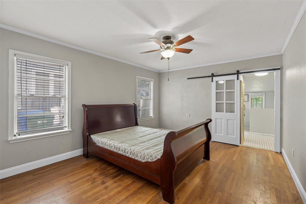 2530 Colcord Avenue Waco, TX 76707 - Photo 14 of 23 Bedroom with a barn door, wood finished floors, baseboards, crown molding, and a ceiling fan