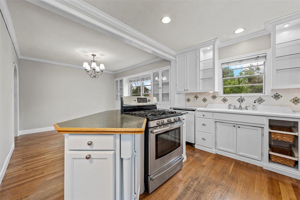 2530 Colcord Avenue Waco, TX 76707 - Photo 10 of 23 Kitchen with stainless steel gas stove, hardwood / wood-style floors, decorative backsplash, white cabinets, and crown molding
