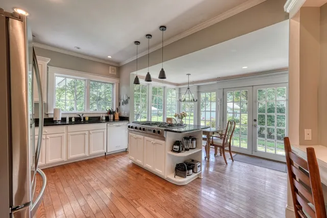 a large kitchen with stainless steel appliances kitchen island granite countertop a table and chairs