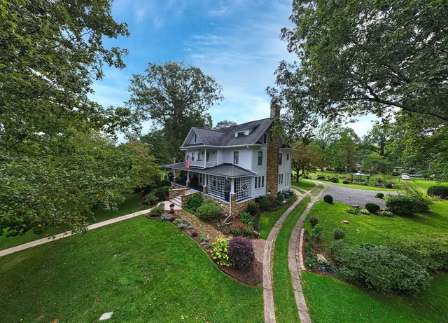 a view of a house with a big yard plants and large trees