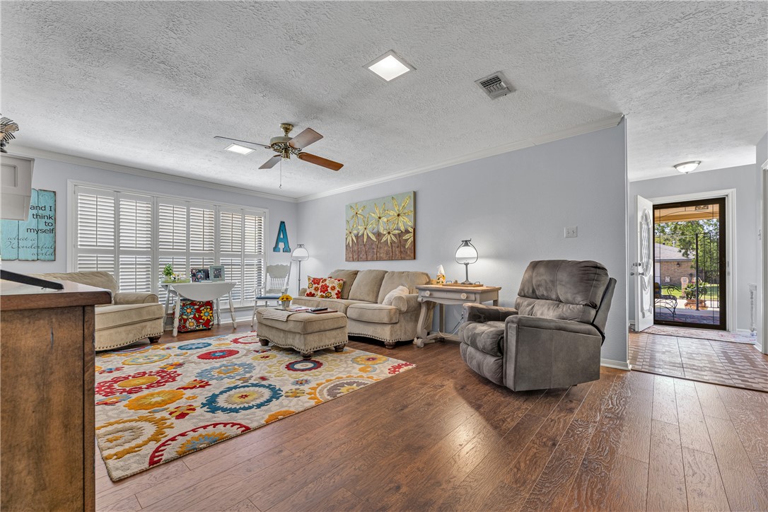 2911 Braeburn Street Bryan, TX 77802 - Photo 10 of 30 Living area featuring wood-finish flooring, white plantation shutters, a ceiling fan with light fixture, and recessed lighting.