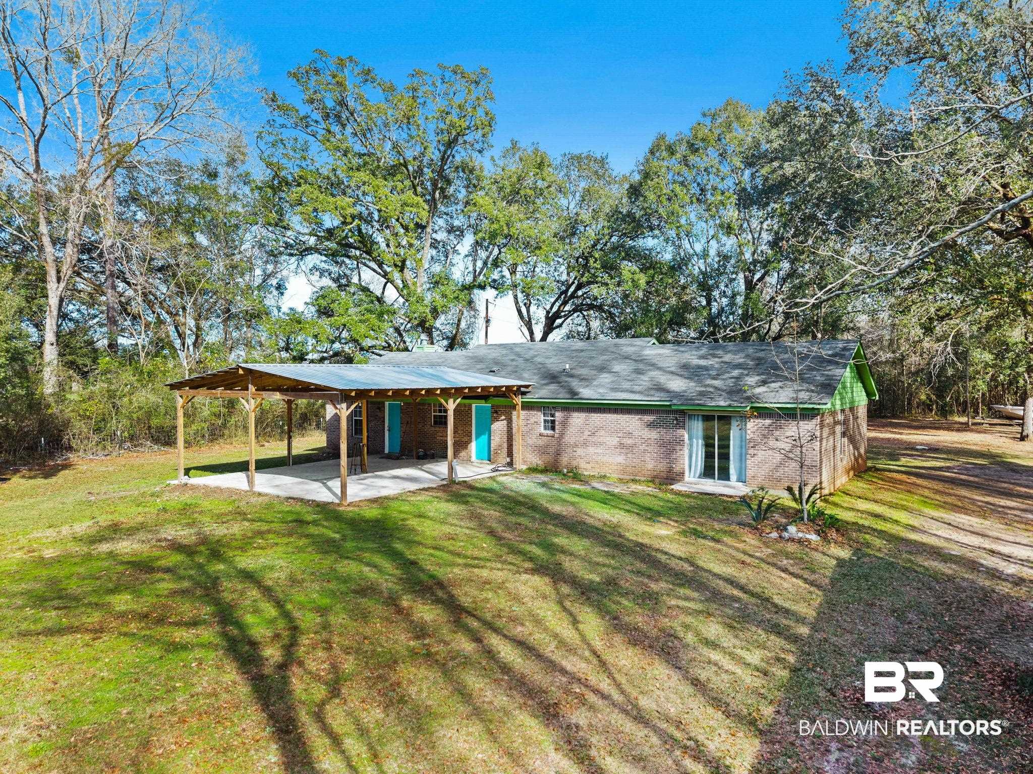 17366 Old Brady Road Bay Minette, AL 36507 - Photo 38 of 43 Rear view of house featuring an attached carport, a patio, brick siding, and a lawn