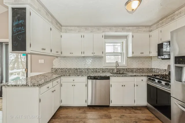 a kitchen with stainless steel appliances granite countertop a stove a sink and white cabinets