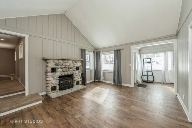 an empty room with wooden floor fireplace and windows