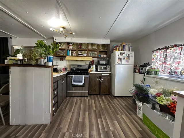 a kitchen with stainless steel appliances granite countertop a refrigerator a stove and a wooden floors