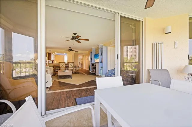 a living room with furniture a large window and wooden floor
