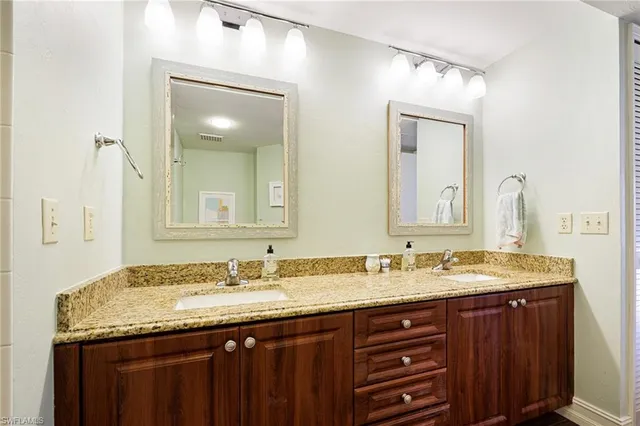 a bathroom with a granite countertop double vanity sink and a mirror