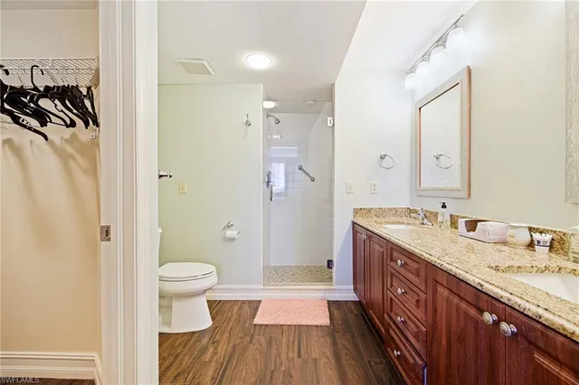 a spacious bathroom with a granite countertop sink toilet a shower and a mirror