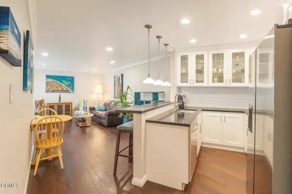 a kitchen with a refrigerator a stove a sink dishwasher a dining table and chairs with wooden floor