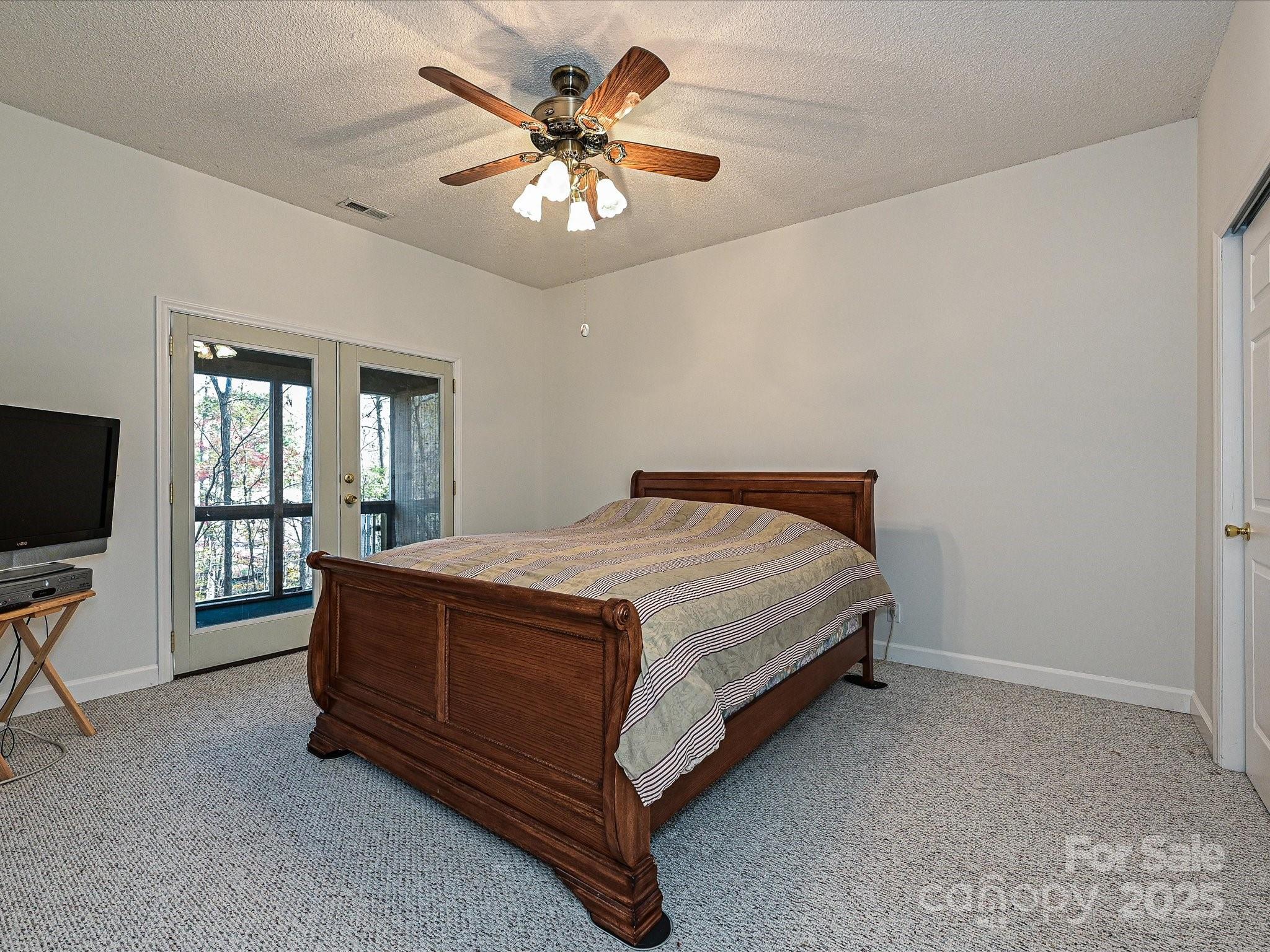 25040 Timberlake Drive Tega Cay, SC 29708 - Photo 31 of 40 a spacious bedroom with a bed and a chandelier