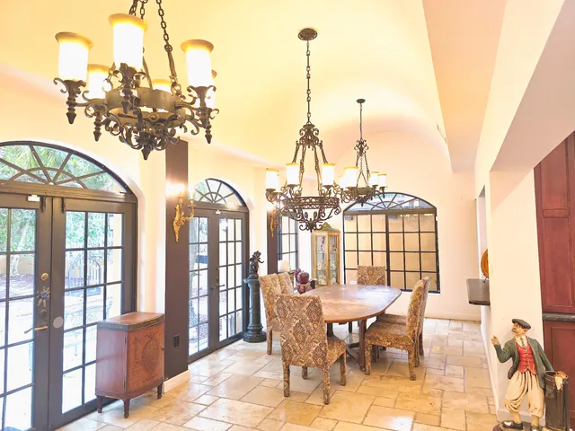 a view of a dining room with furniture a chandelier and large windows