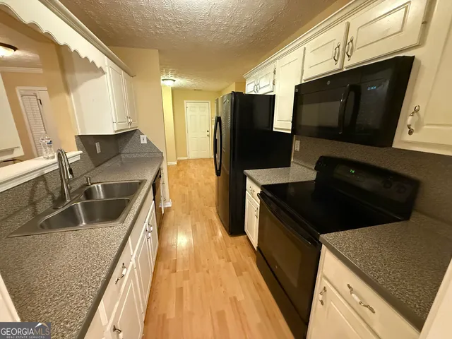 a kitchen with stainless steel appliances a stove a microwave a sink and a refrigerator