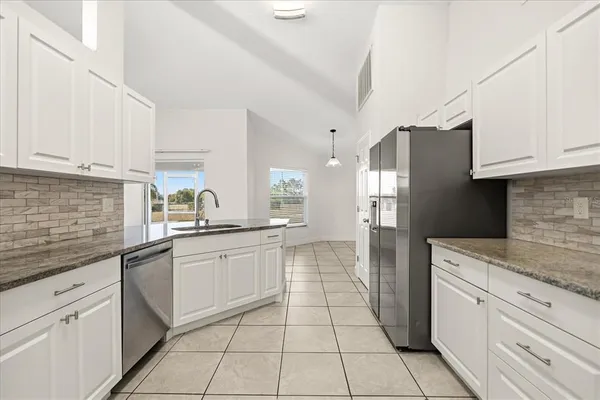 a kitchen with stainless steel appliances granite countertop a sink and dishwasher a stove top oven with white cabinets