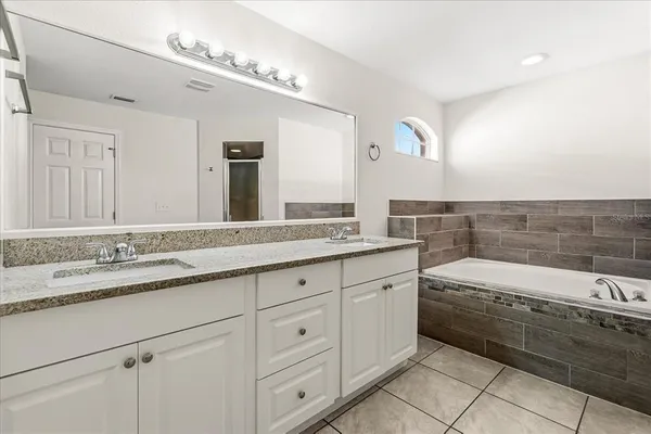 a bathroom with a granite countertop bathtub a sink and a mirror