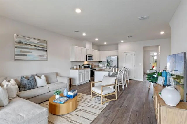 a living room with furniture kitchen and a wooden floor