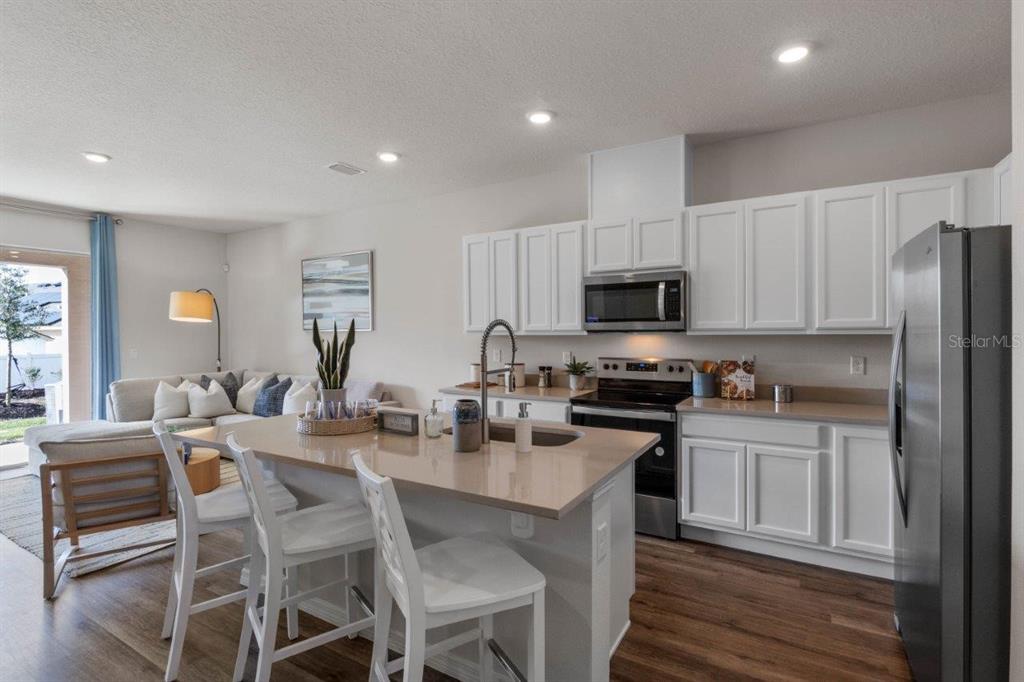 2729 Gladiola Road Winter Haven, FL 33884 - Photo 6 of 25 a kitchen with stainless steel appliances granite countertop a stove a sink a microwave a dining table and chairs