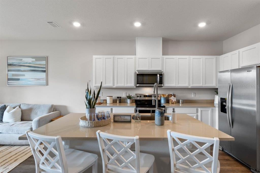 2729 Gladiola Road Winter Haven, FL 33884 - Photo 9 of 25 a kitchen with stainless steel appliances a dining table chairs stove refrigerator and microwave