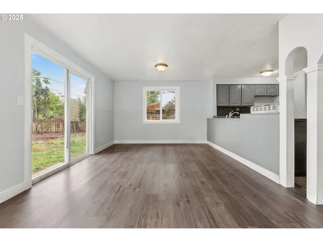 a view of a kitchen with wooden floor electronic appliances and windows