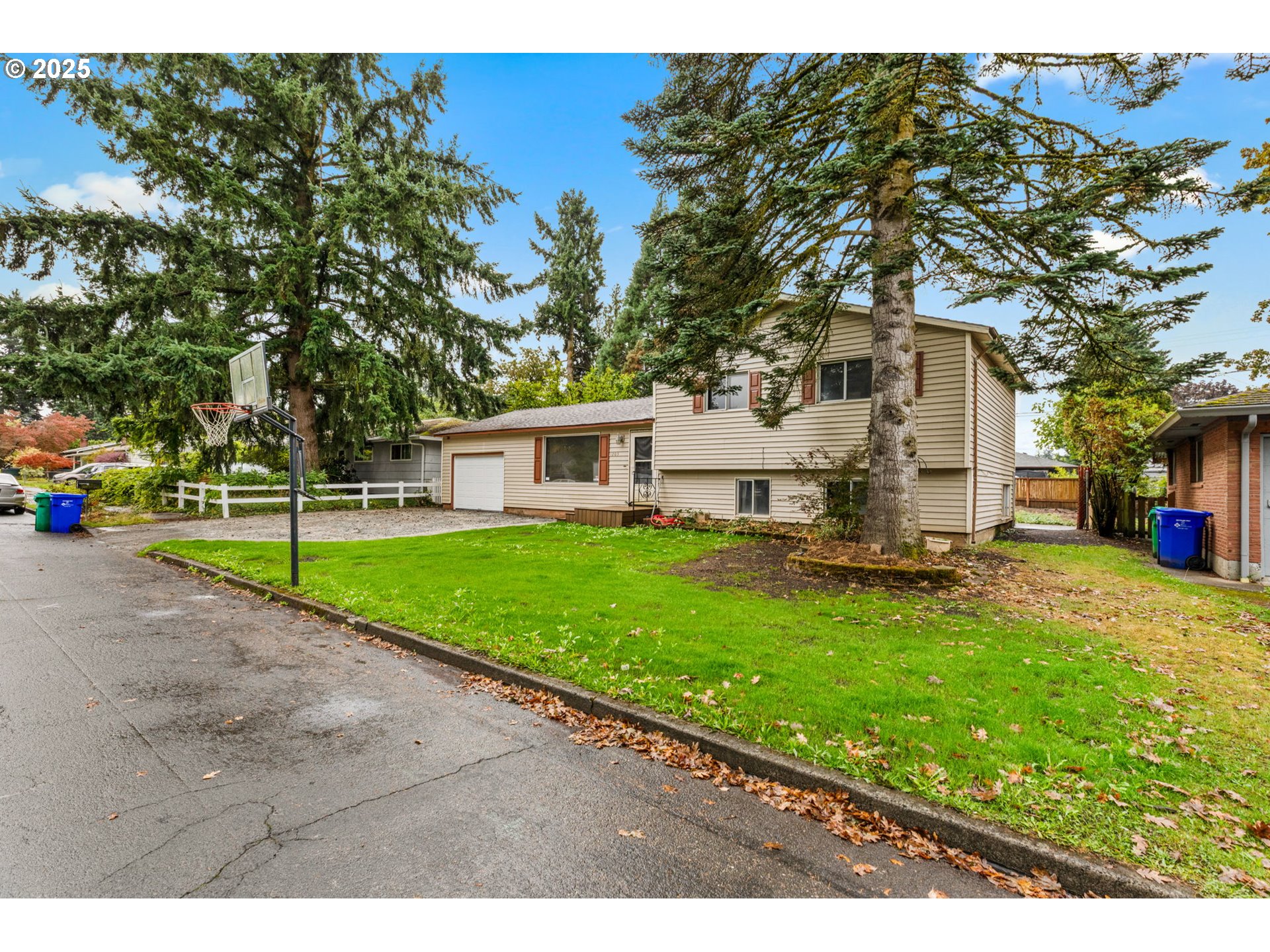 1203 Northeast 190th Place Portland, OR 97230 - Photo 3 of 48 a view of a white house in front of a big yard with plants and large trees