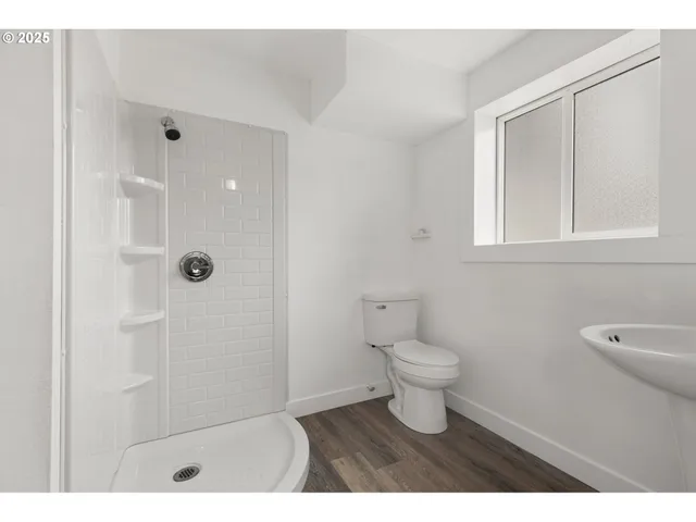 a bathroom with a toilet a sink a shower and a window