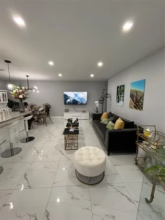 a living room with furniture a table and kitchen view