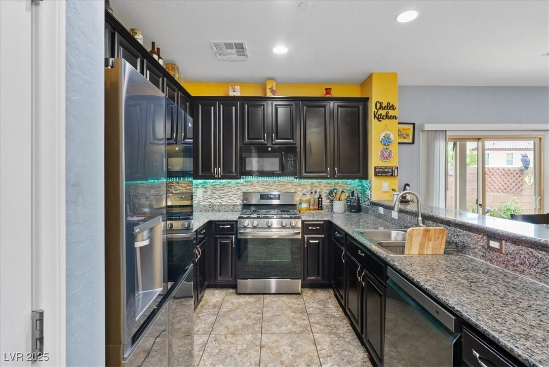 9040 Magnetic Court Las Vegas, NV 89149 - Photo 5 of 43 Kitchen with black appliances, light stone countertops, dark cabinets, and recessed lighting