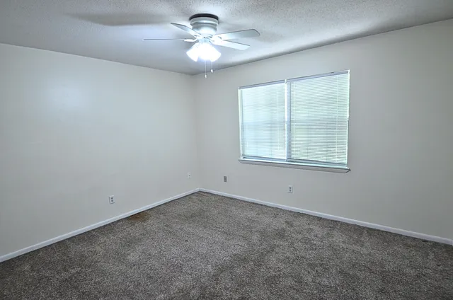 an empty room with a window and a fan