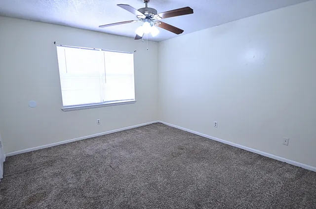 an empty room with a window and a fan